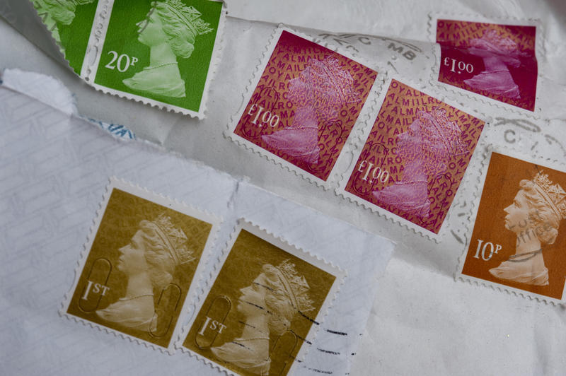 Background of cancelled British postage stamps on correspondence and letters in a snail mail concept