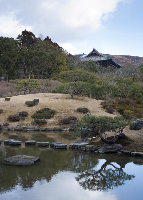 Stepping stones across the lake in the Isuien garden with the Nandaimon Gate of Todaiji temple in the background