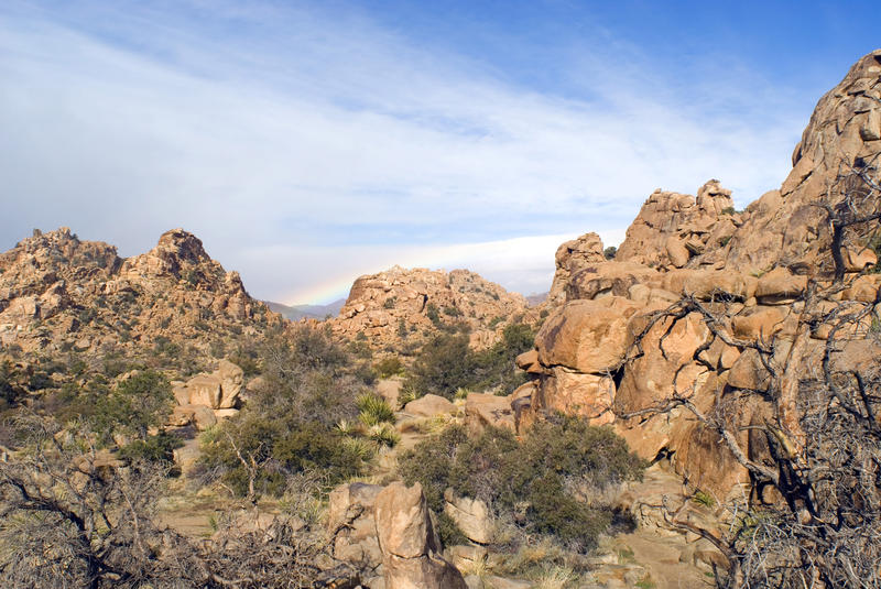 rocky desert landscape with a distant rainbow, joshua tree national park, california