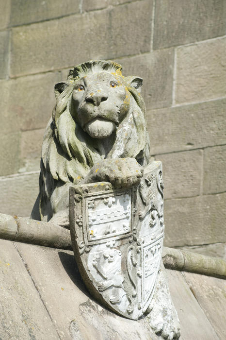 The stone sculpture of the lion with its heraldic shield on the Gothic revival Cardiff Castle Animal Wall at Cardiff Castle in Wales