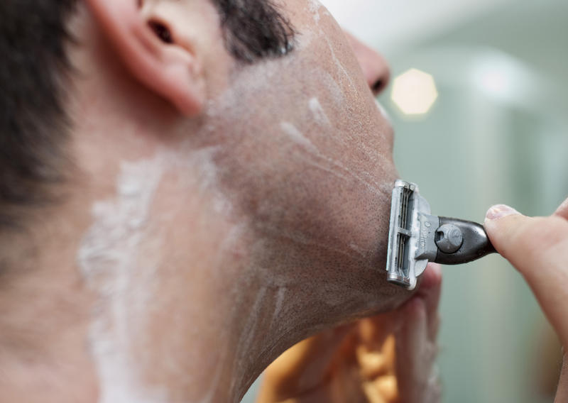 Close cropped shot of a man shaving with a hand held wet razor and soap
