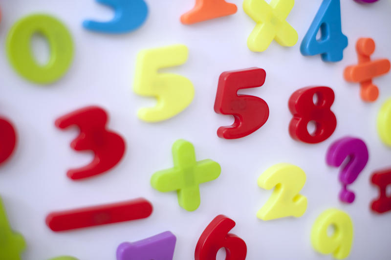 Colorful stick-on numbers and mathematical symbols stuck on a fridge door