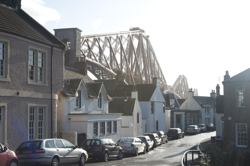 Street view in North Queensferry, Scotland, with the Forth Rail Brdge towering behind the buildings