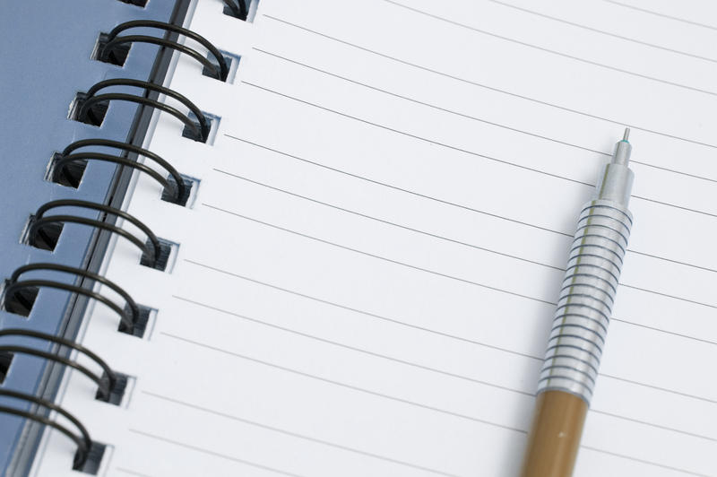 Mechanical pencil lying on the lined blank page of a ringbound notepad
