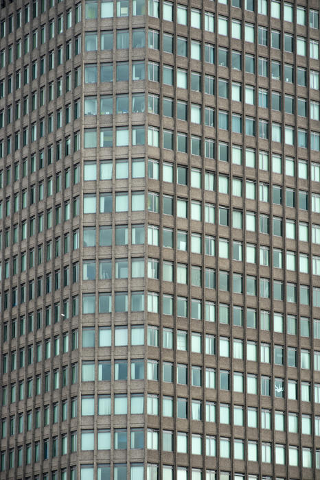 Exterior of a modern office block skyscraper with multiple small windows in daylight