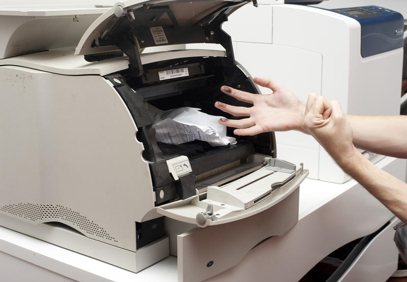 Man shaking his fist in impotent anger at a paper jam in an office copier or printer