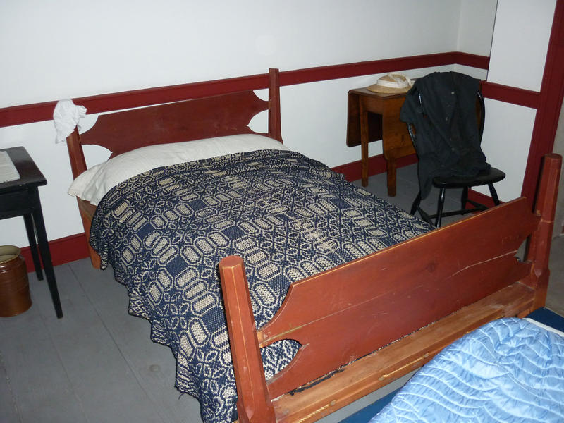 Double wooden bed with bedclothes and side tables in an empty hotel bedroom interior