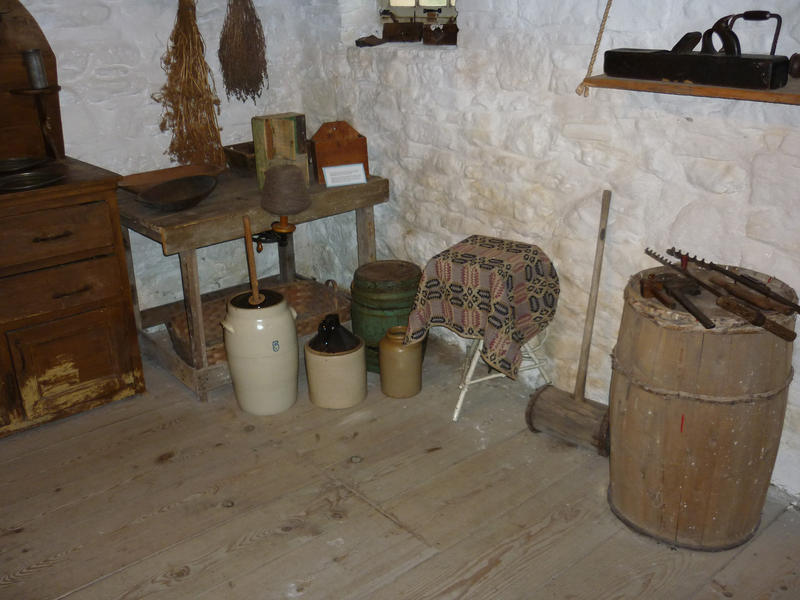Interior of a vintage simple country kitchen with rudimentary furniture and implements and ceramic storage jars