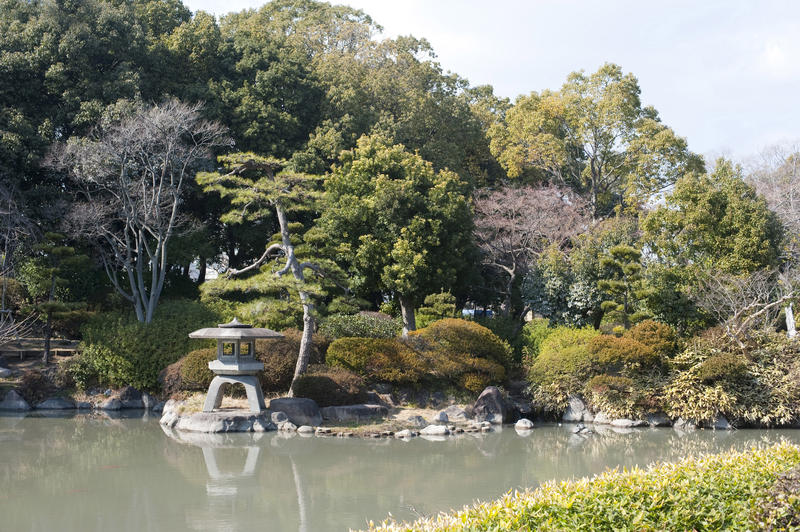 Stone lantern and a tranquil pond at a fromal Japanese garden, in osaka, Japan