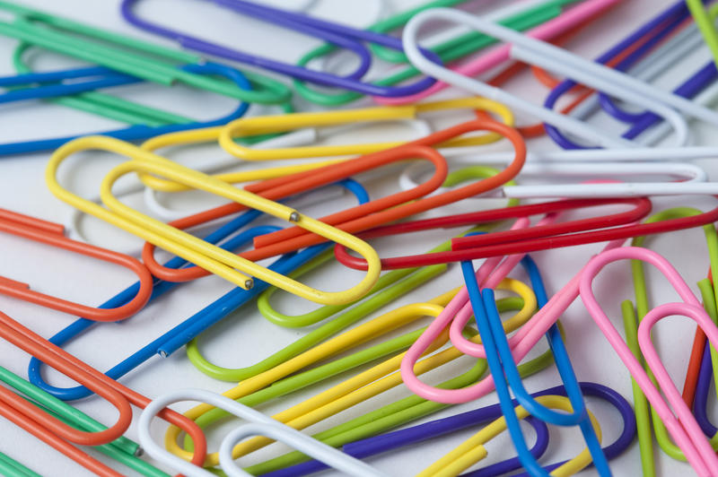 Closeup of randomly scattered colourful paperclips on a white background