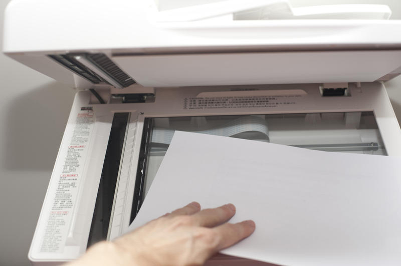 Male hand placing a document on the glass surface in a copier in order to make a copy of the text