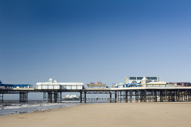 View across the deserted sandy beach to the Blackpool central pier with plenty of copyspace in a clear sunny blue sky