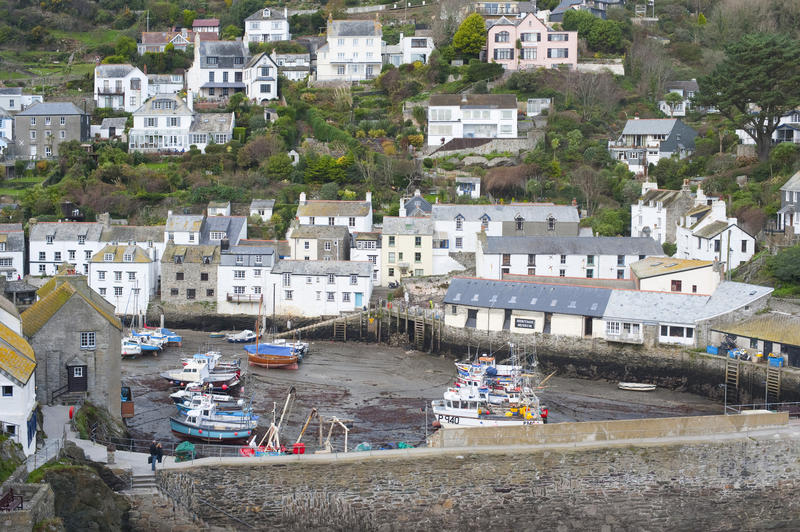 Polperro fishing village, Cornwall with a high angle view of boats beached in the harbour at low tide and the quaint white-washed cottages on the hillside behind