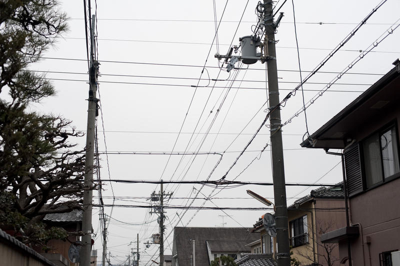 a common sight in japan, power and communications cables strung down the street from poles