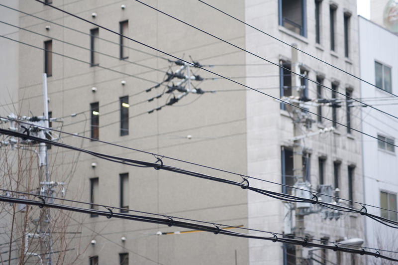 a complex network of overhead electricity cables crisscrossing a city ctreet