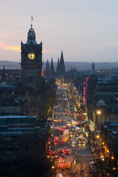 View of the colourful scene on Princes Street Edinburgh at night looking down past the Balmoral Hotel clocktower