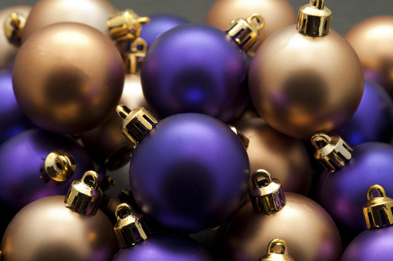Closeup background of round shiny purple and gold Christmas baubles in a random pattern
