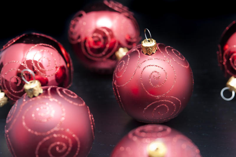 Red Christmas ornamental baubles with glitter curlicues on a dark background