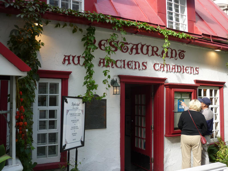 Exterior of Aux Ancien Canadiens Restaurant, Quebec city, Canada with tourists viewing the menu
