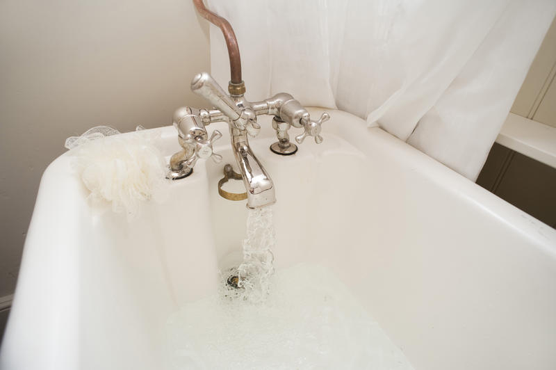 Running an enjoyable hot bath with water flowing from a retro faucet on a vintage bathtub