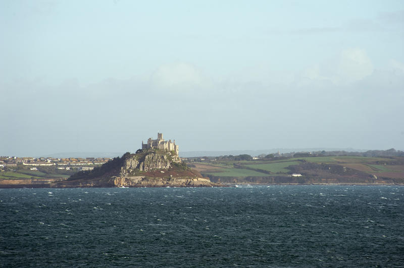 View across Mount Bay of the tidal island of St Michaels Mount with the town of Marazion on the mainland and the castle visible on top of the island