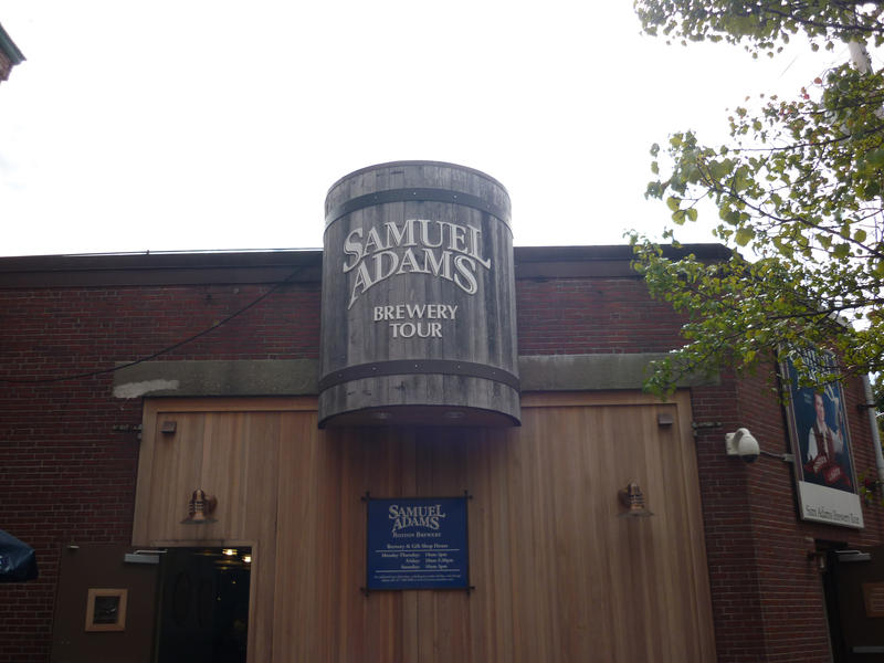 Entrance to Samuel Adams Brewery building with a large beer barrel shaped sign over the doorway