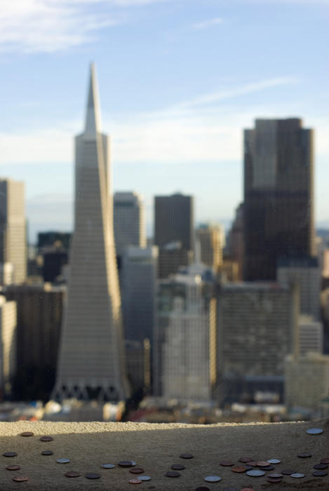 coins dropped from the coit tower to make a good luck wish with the city skyline out of focus in the distance