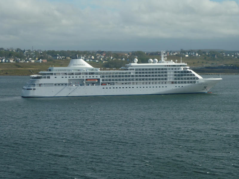 Silversea passenger cruise liner sailing along parallel to urban coastline during one of its vacation voyages