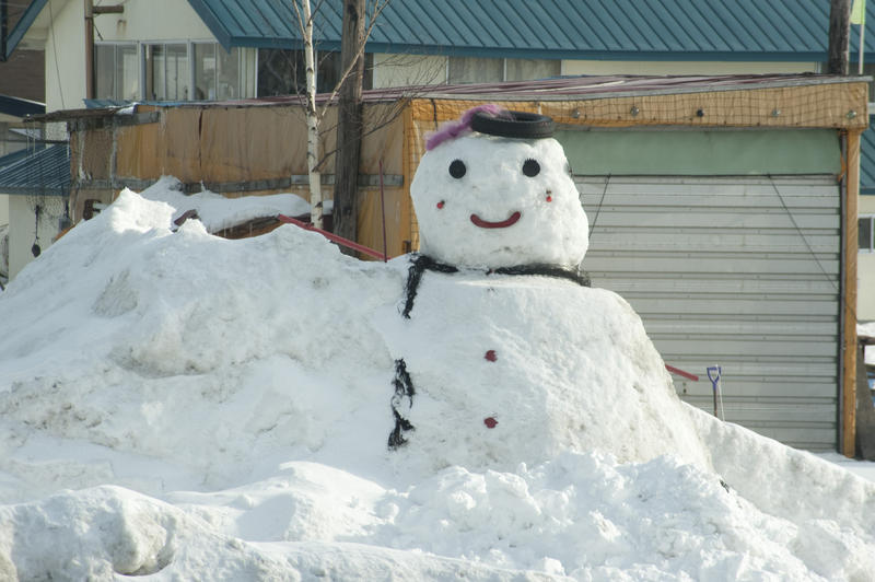 A large snowman built in ploughed snow.