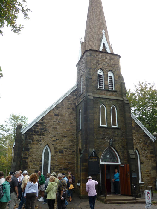 Old historical building of St George Church, Nova Scotia with a crowd of tourists or congregation standing outside admiring the steeple