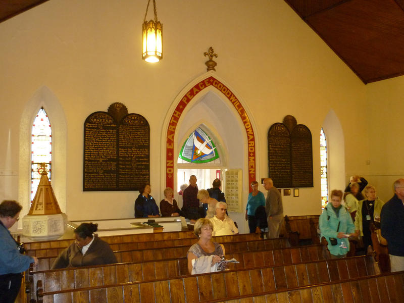 Interior of St George Church looking towards the door with members of the congregation entering and taking seats in pews