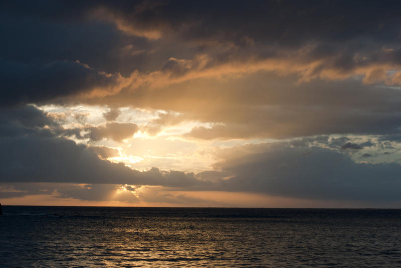 Glowing sunset breaking through the clouds over the ocean letting through a shaft of light