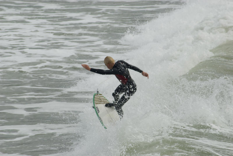 surfer riding his board through the cold pacific waters of a california winter - not model released