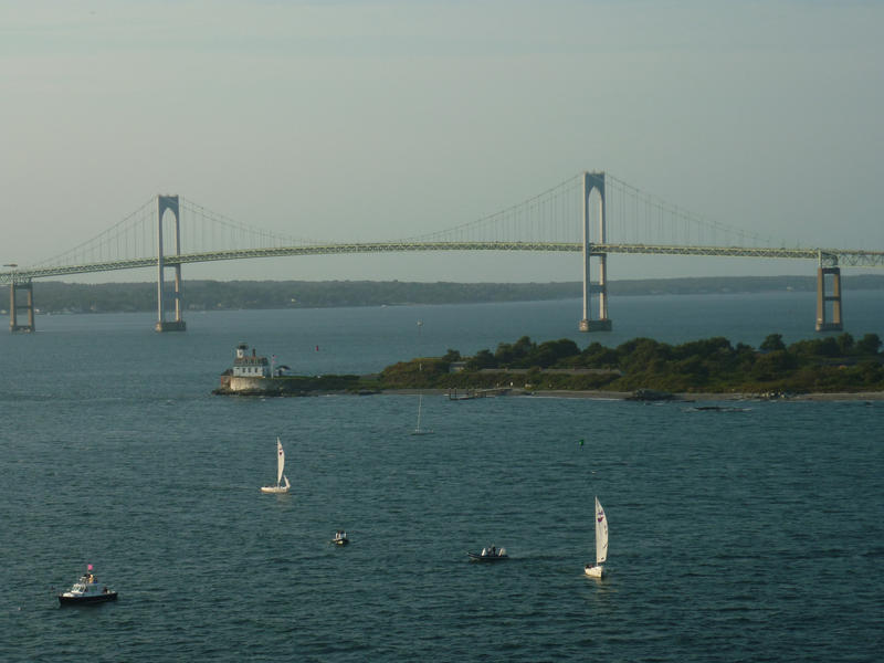 Long suspension bridge silhouetted against the skyline over water with small pleasure yachts out sailing in the foreground