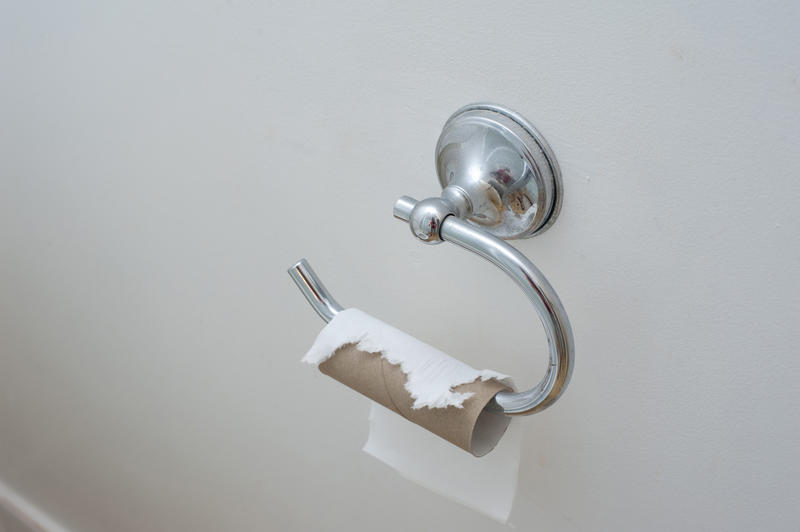 Toilet paper holder on white wall with an empty roll of paper