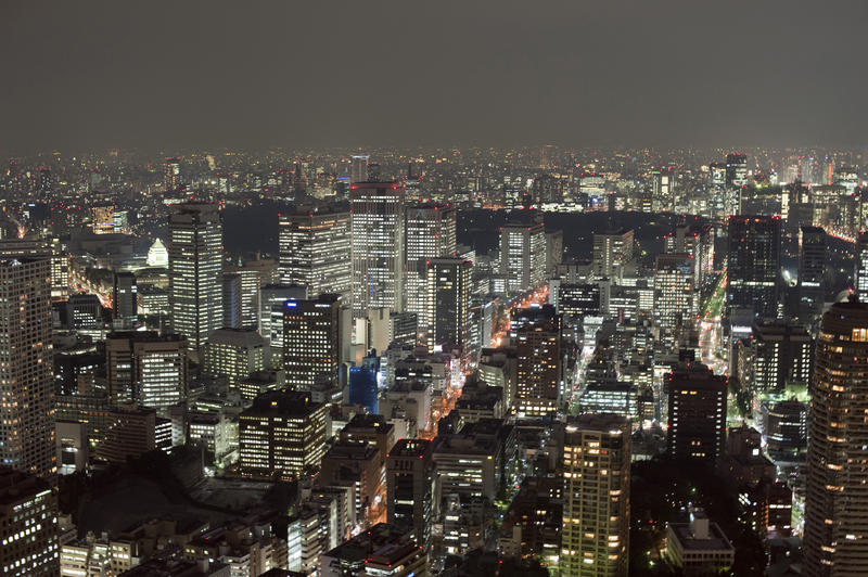 tall office buildings in tokyo brightly lit at night