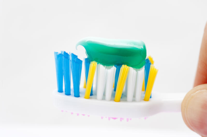 Closeup of the bristles of a plastic toothbrush with cool green toothpaste