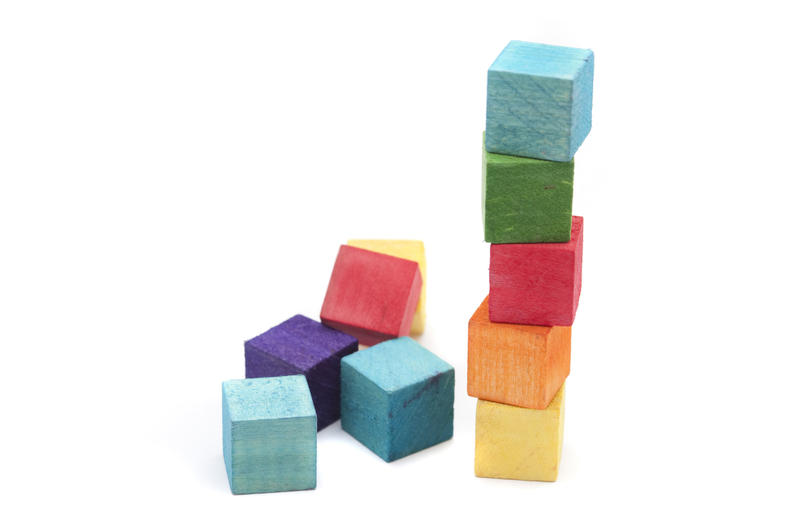 Colourful toy wooden building blocks or cubes stacked into a tower useful as an educational aid in teaching children to count and hand coordination