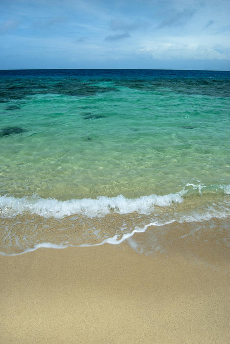 Beautiful turquoise ocean with gentle surf lapping on the golden sand of the beach