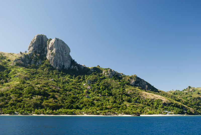 View of Waya Island , Fiji, from the sea showing the lush vegetation covering the hillside above a golden sandy beach