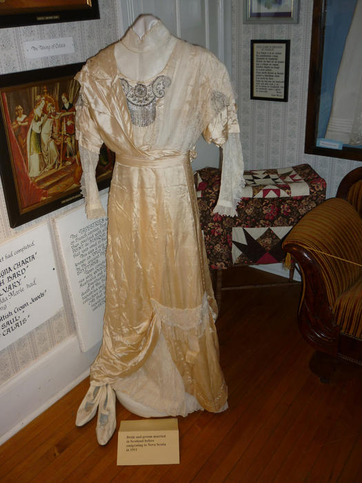 Antique wedding dress on display in a museum with the material beginning to yellow with age