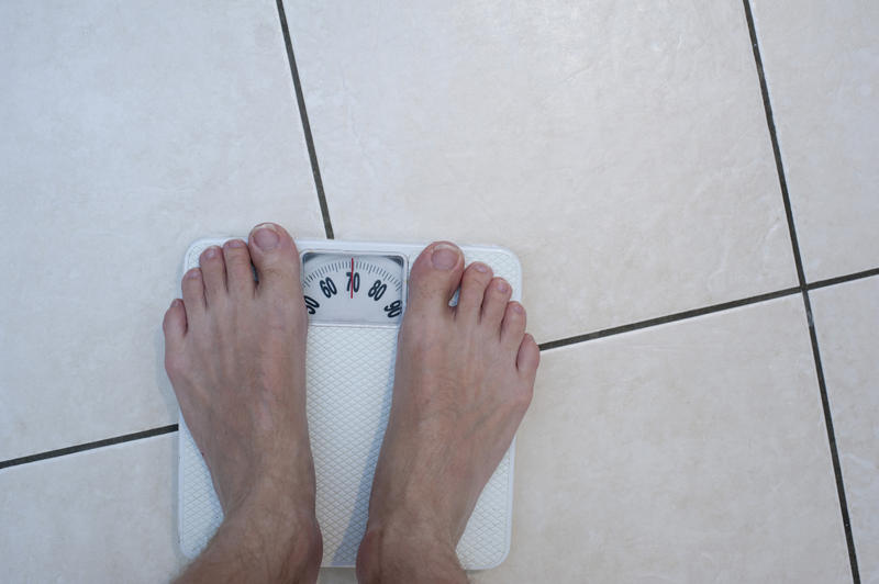 View from above on male feet on bathroom scale