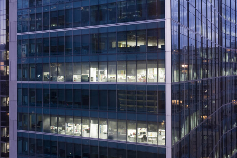 Working late at night concept looking in through the illuminated windows of a highrise urban office block at night