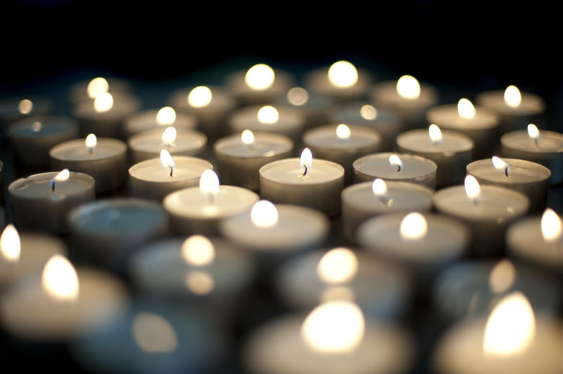 Seasonal background with an array of burning Christmas candles with festive twinkling flames on a black background with shallow dof