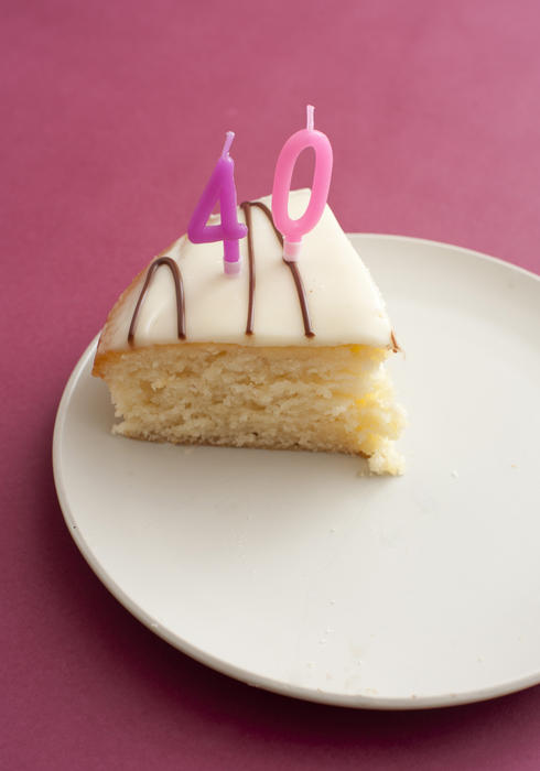 Slice of 40th birthday cake with pink candles marking the years served on a plate over a deep pink or magenta background, high angle view