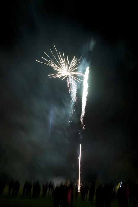 Crowds watching a fireworks display on 5th November or Guy Fawkes, also called Bonfire Night, as rockets explode in a shower of sparks in the night sky