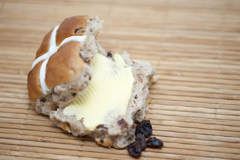 Delicious buttered fresh spicy Easter Hot Cross Bun with raisins