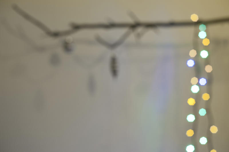 Abstract Christmas background with a string of defocused colorful lights hanging from a twig forming a border, with copy-space for your greeting