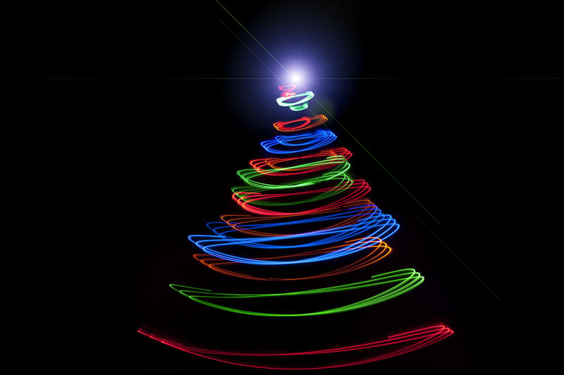 Abstract festive Christmas tree formed of spiralling multicoloured lights with bright star at the top shining in the darkness