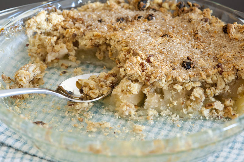 Spicy apple crumble half eaten in a bowl topped with a delicious spicy mixture of raisins, cinnamon and sugar